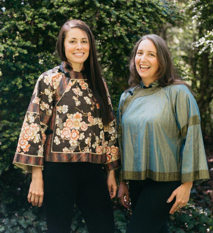 Two women standing side by side outdoors in View A. Woman on left is in a cotton floral fabric and woman on right is wearing a light green silk jacket.