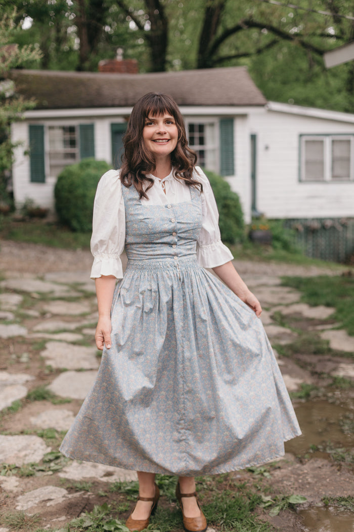 Woman walking on stone path wearing Dirndl View A. Dress is light blue.