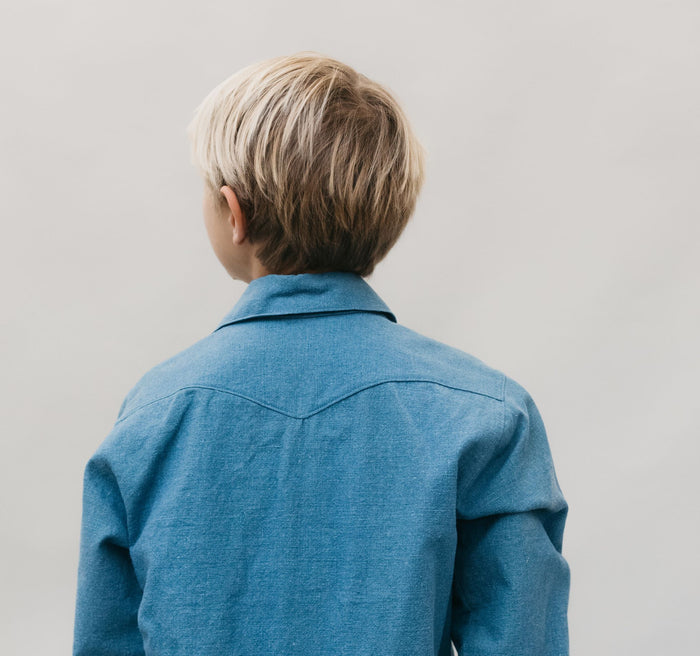 Close up of small blonde boy standing in front of a white studio backdrop wearing 218 Child's Frontier Shirt with shaped back yoke.