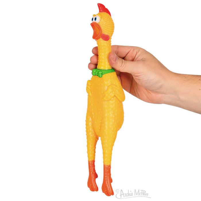 A hand grasping a squealing toy, the Champion Rubber Chicken, which is the classic yellow rubber chicken accented with a dapper green bow tie.