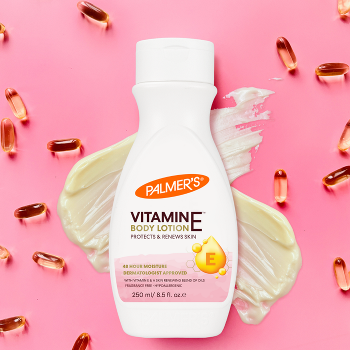 Palmer's Vitamine E body lotion bottle with pink background and scattered capsules.