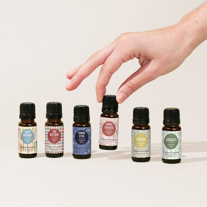 Hand reaching towards a row of essential oil bottles with labels on a light background