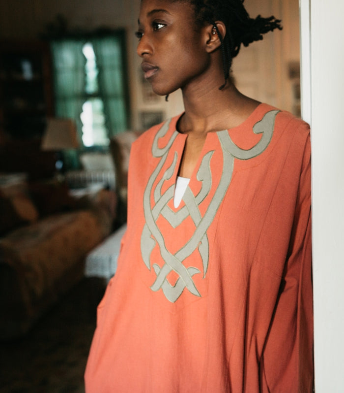 Close up photo of model in coral colored Egyptian Shirt.  Shows details of gray applique on front.