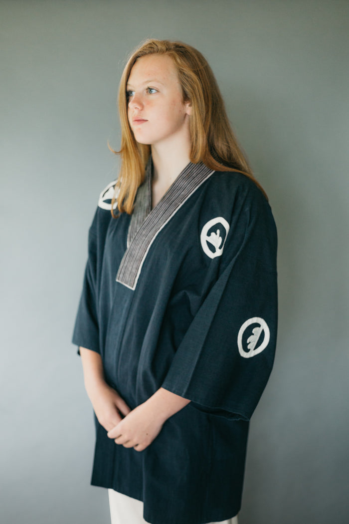 Young woman standing with hands in front of her wearing traditional Hapi Jacket..