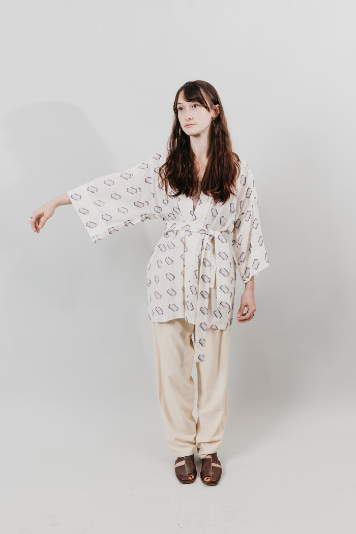 Woman wearing a white and blue printed Hapi, belted at the waist.