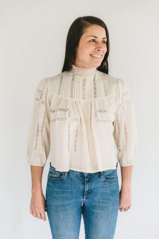 Brunette woman smiling, standing in front of a white studio backdrop wearing 206 Gibson Girl Blouse.