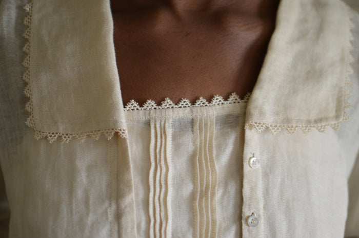 Close up of 210 Armistice Blouse long collar forming a deep rectangle, trimmed with lace at the edges of the collar worn by African woman