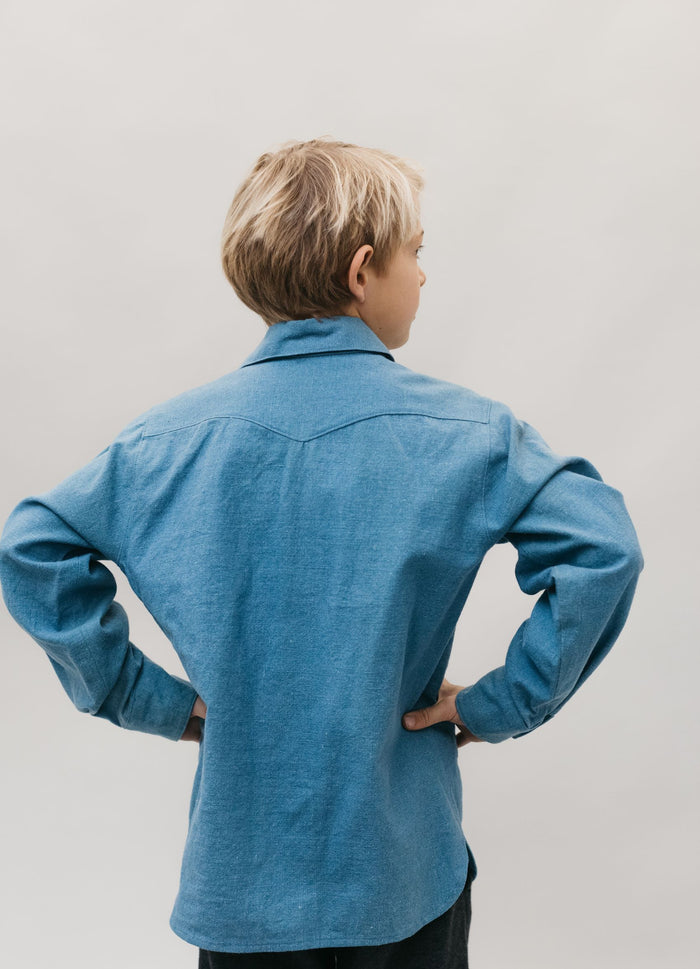 Back view of small boy with hands on his hips standing in front of a white studio backdrop wearing 218 Child's Frontier Shirt with shaped back yoke.