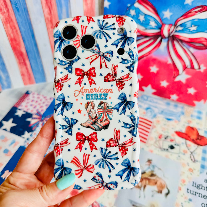 Hand holding the American Girly Wavy Luxe MagSafe iPhone case, showing the red, white and blue bow print with cowboy boots and American Girly lettering.