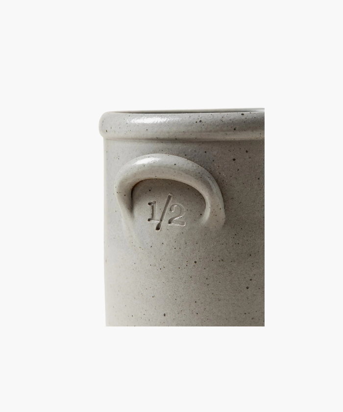 A detailed picture of a gray stoneware crock highlighting the color, texture, and size.  This crock has a subtle embossed "1/2" under the handle, conveying a rustic, artisanal feel.