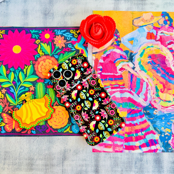 Trendy black wavy iPhone case featuring an intricate folk art botanical pattern of red flowers, magenta details, and yellow fan petals with a high-gloss finish.