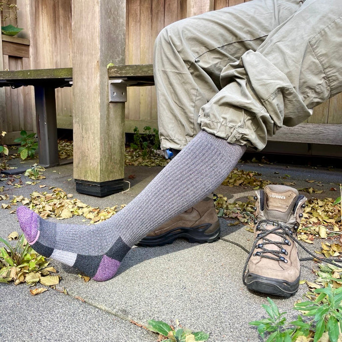 Knee-high socks with a color block design, worn with cargo pants and hiking boots, on a leaf-strewn surface.