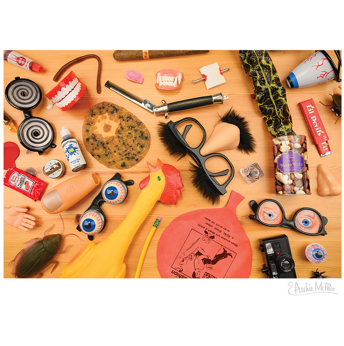 On the table is Dad's Joke Drawer Puzzle, featuring items like a rubber chicken, funny glasses, fake teeth, and a whoopee cushion. It's an ideal humorous gift for someone who loves a good laugh.