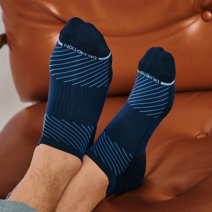 Navy ankle compression socks with blue diagonal stripes, resting on a brown leather surface.
