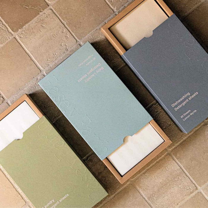 Three open boxes of detergent sheets on a tiled surface.