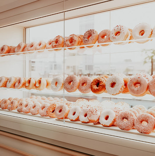 A display case filled with rows of assorted donuts.