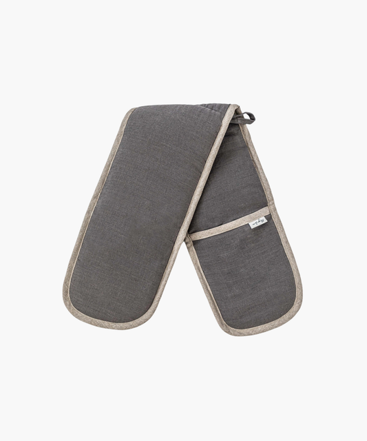 A pair of dark gray oven mitts with beige trim, linked together. They have a pocket on one side and a small loop for hanging, conveying functionality. | Wildwood Home Co.