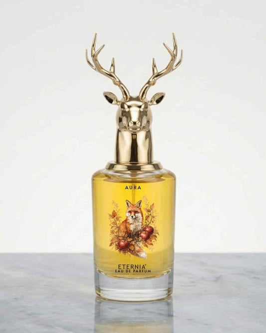 Glass eau de parfum bottle with gold deer antler cap, yellow liquid, front labels