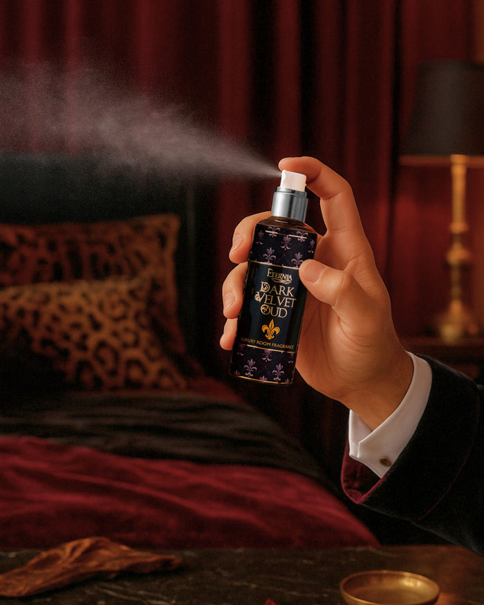 Hand holding Eternia® Dark Velvet Oud room spray bottle with mist and metallic pump sprayer.