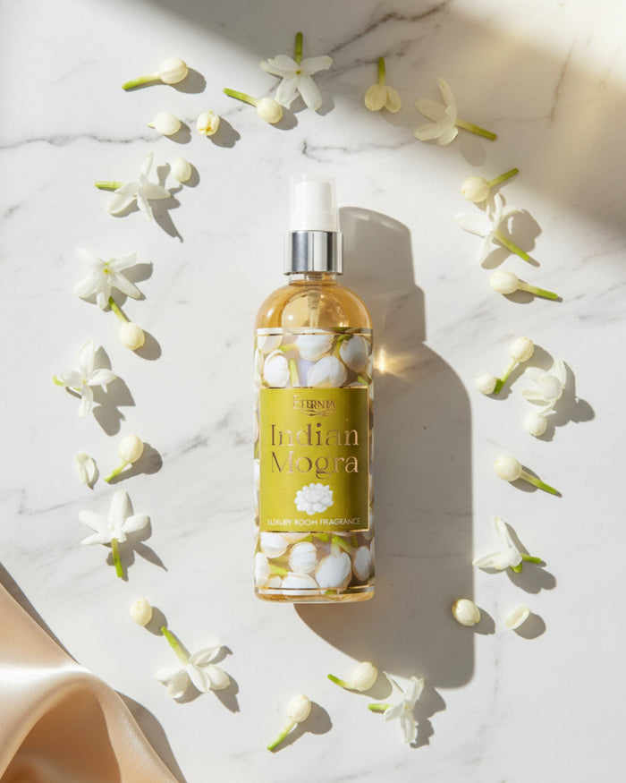 Indian Mogra room spray bottle surrounded by white blossoms on a marble surface.