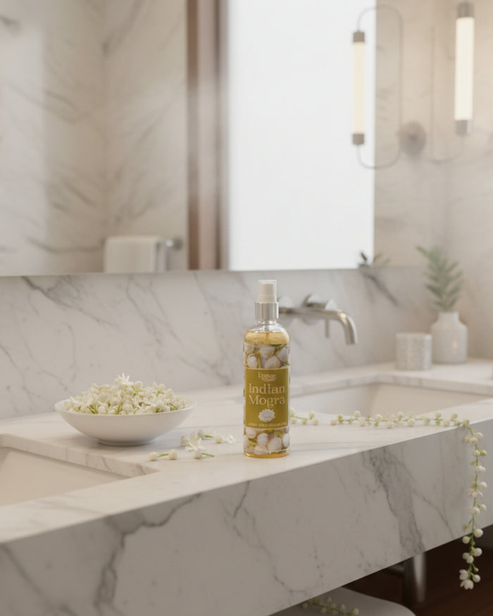 Indian Mogra room spray bottle on a countertop with a bowl of blossoms nearby.