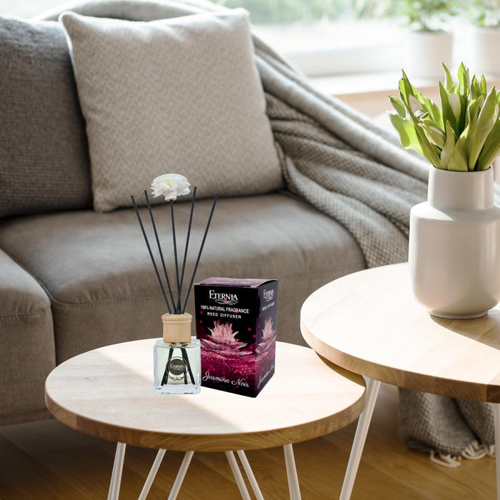 Reed diffuser set on a table with a glass bottle, rattan reeds, and packaging