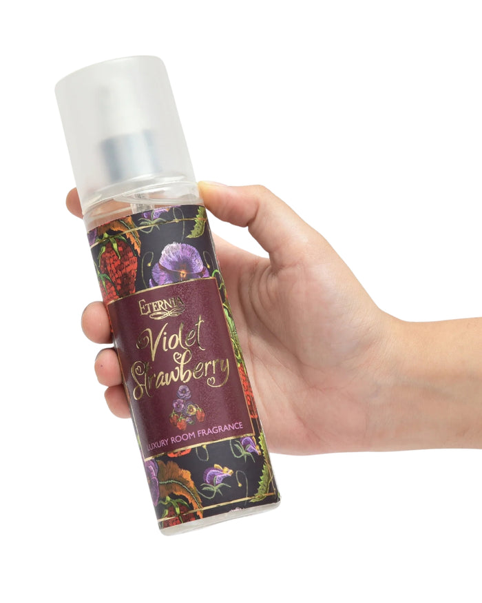 Room spray bottle held in hand, white cap, Violet Strawberry dark label