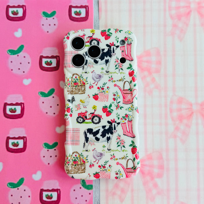 Farm Girl Cutie Wavy Luxe MagSafe iPhone case flat lay on pink strawberry jam and gingham paper, showing the full farm illustration print.