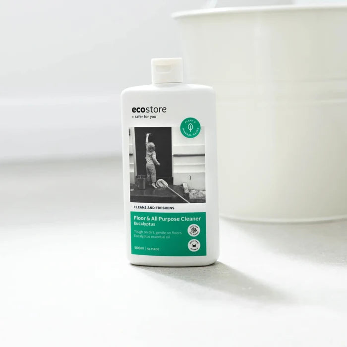 Bottle of all purpose cleaner on a clean white floor next to a white metal bucket.