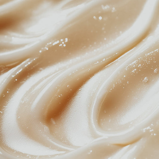 Close-up of a creamy, beige-colored fragrance oil with a smooth texture, possibly containing glitter or fine particles for visual appeal.