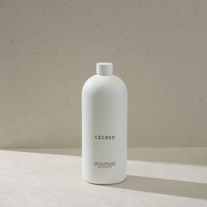 Cécred Hydrating Conditioner max size bottle with flip cap, standing on a beige surface against a tan textured background