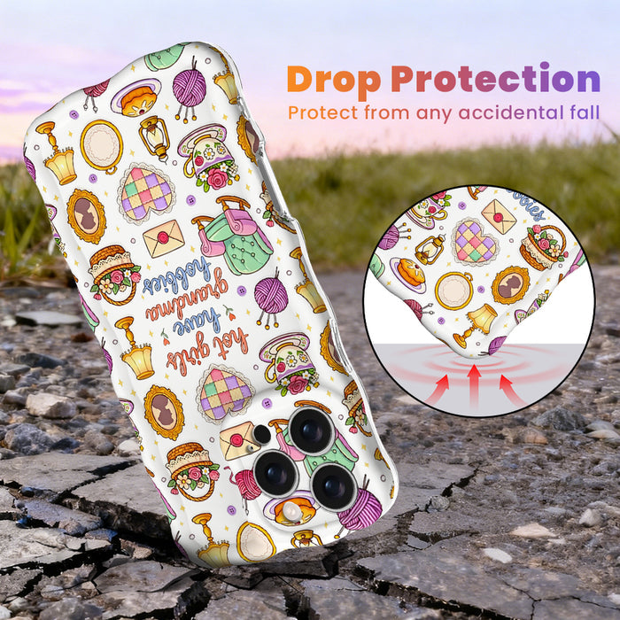 Trendy wavy iPhone case featuring a whimsical grandmacore pattern of yarn, rocking chairs, teacups, and a "hot girls have grandma hobbies" quote with a high-gloss finish.