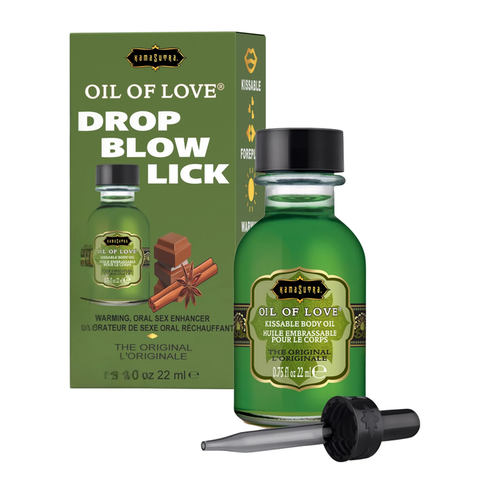 A product shot featuring the green "Oil of Love" bottle and its packaging. The green box displays the text "DROP BLOW LICK" in large white and yellow letters, alongside an illustration of chocolate squares and cinnamon sticks. Icons on the side of the box indicate "Kissable," "Foreplay," and "Warming."
