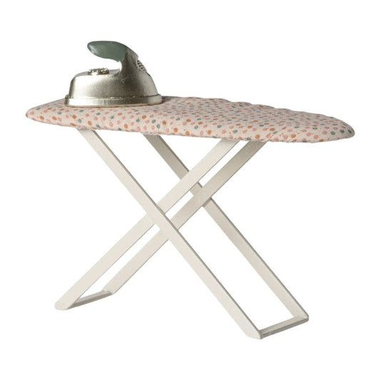Folding ironing board with floral cover and iron on a white background