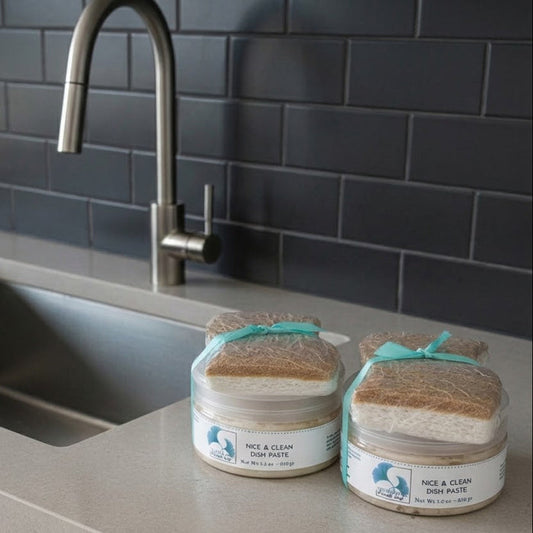 Two jars of Nice & Clean Dish Paste on a kitchen counter with a sink and tiled wall in the background.