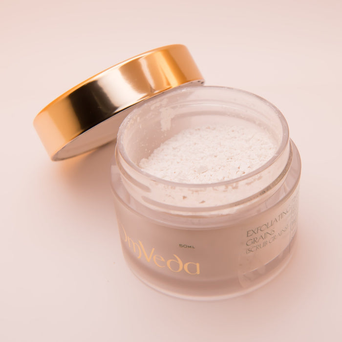OmVeda exfoliating grains jar with open gold lid and off-white scrub inside