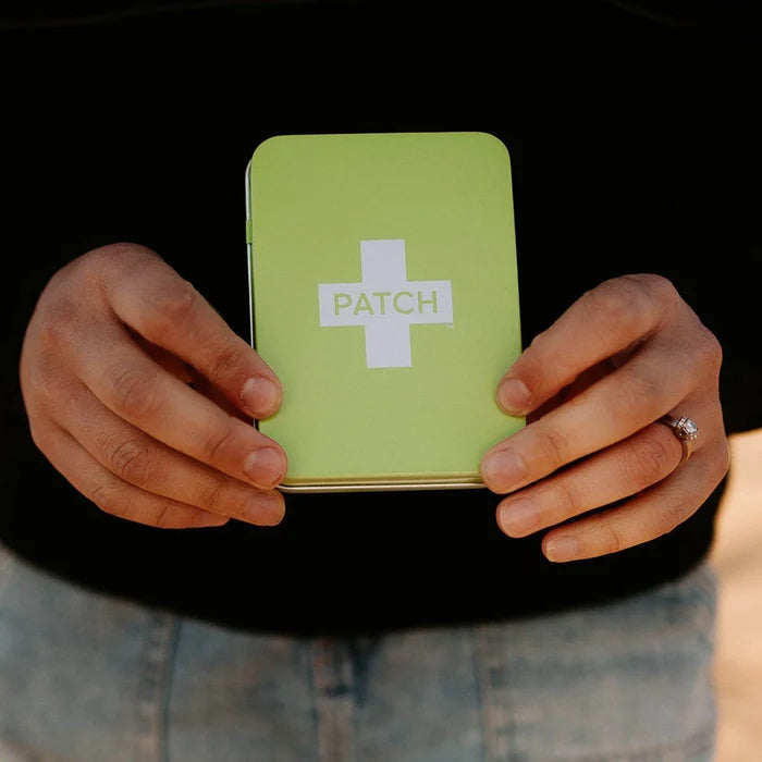 Person holding a green case with 'PATCH' branding against a black background