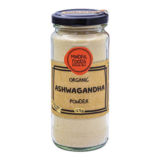 A glass jar of Mindful Foods Ayurvedic Organic Ashwagandha Powder, 12.5g, featuring a beige label and a black lid, set against a plain white background.