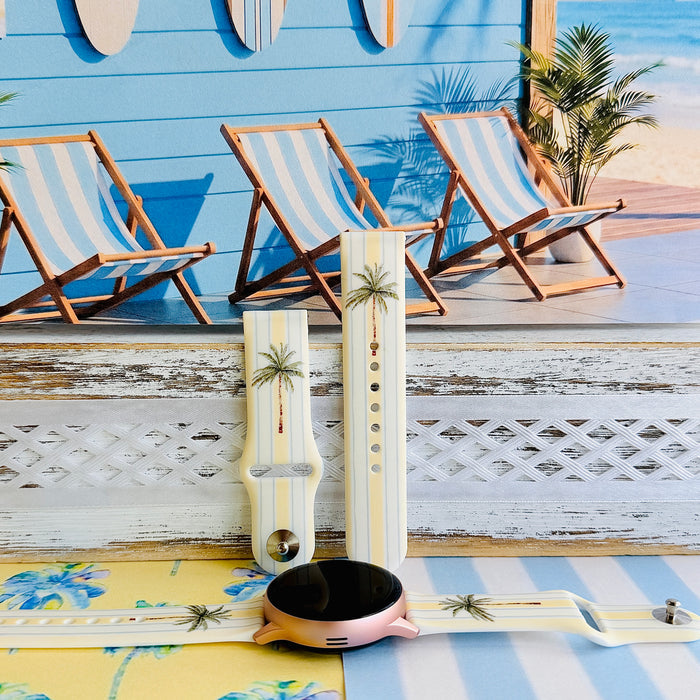 Palm Shore Club silicone Samsung Watch band with hand-painted palm trees over soft blue and yellow cabana stripes on an ivory base, shown displayed and worn on Apple Watch against a coastal beach club backdrop.