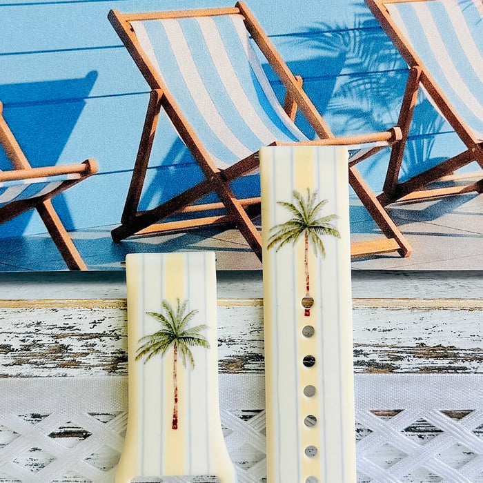 Palm Shore Club silicone Samsung Watch band with hand-painted palm trees over soft blue and yellow cabana stripes on an ivory base, shown displayed and worn on Apple Watch against a coastal beach club backdrop.