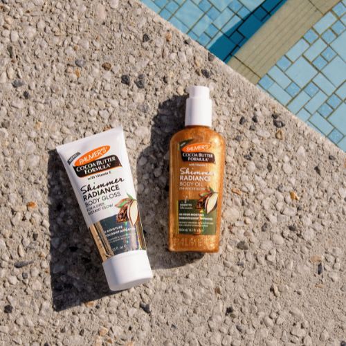 Two Palmers skincare products on a concrete surface near a pool.