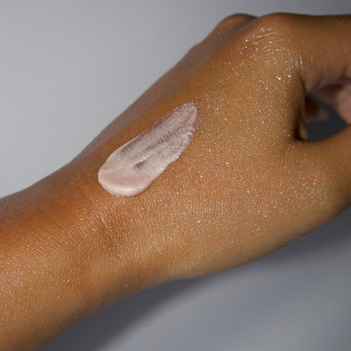 Hand with a shimmering swatch of Palmer's Shimmer Radiance Body Gloss on a gray background