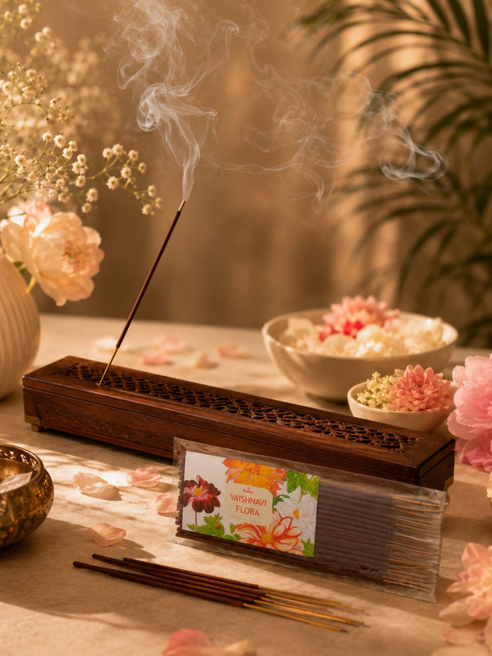 Burning floral incense sticks with soft smoke rising from wooden holder