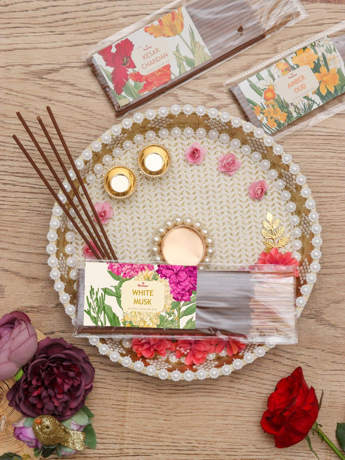 Agarbatti incense sticks with small labeled packets on a decorated round tray
