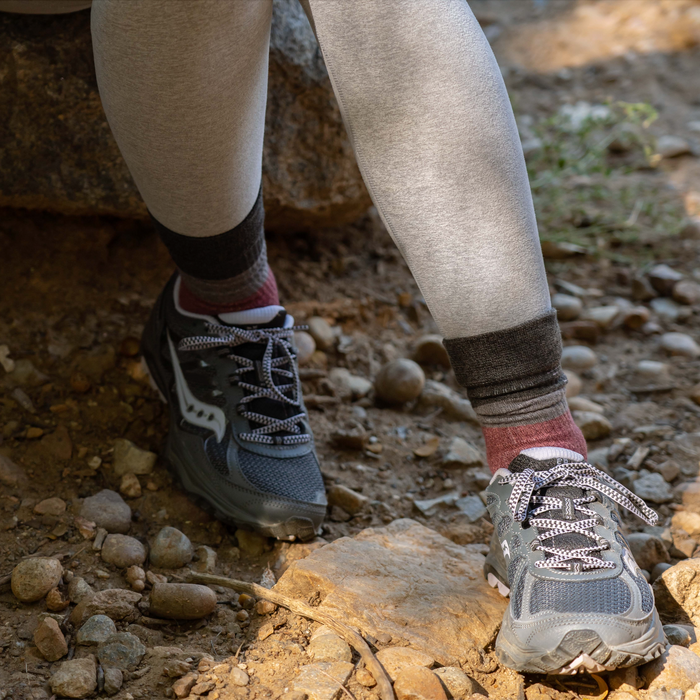 Gray compression leggings with dark cuffs and black athletic shoes on a rocky outdoor surface.