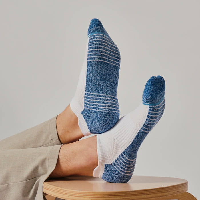 Ankle compression socks featuring a blue and white design, displayed on a wooden surface.