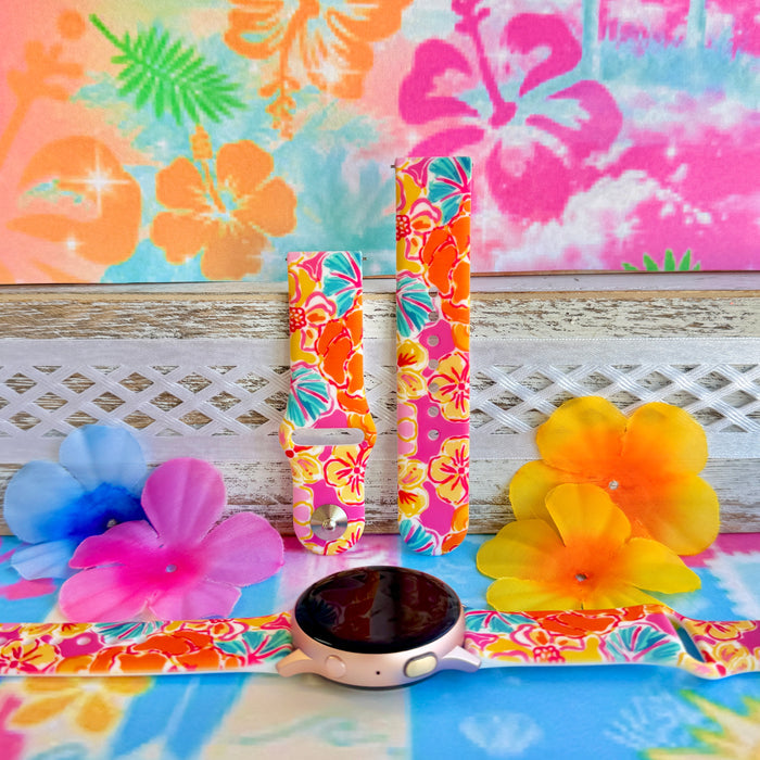 Sunset Hibiscus silicone Samsung Watch band with vibrant pink, orange, yellow, and teal tropical hibiscus floral print, shown displayed and worn on Apple Watch against a colorful tropical floral backdrop.