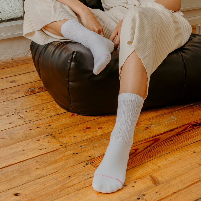 White half-cushion socks with textured design, worn by a person seated on a black bean bag chair.