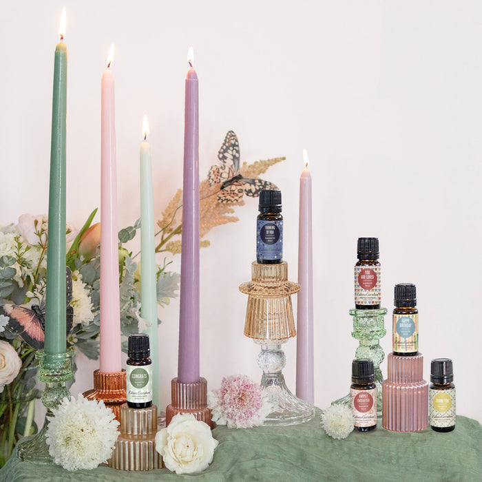 Candles and essential oil bottles on a table with a white background