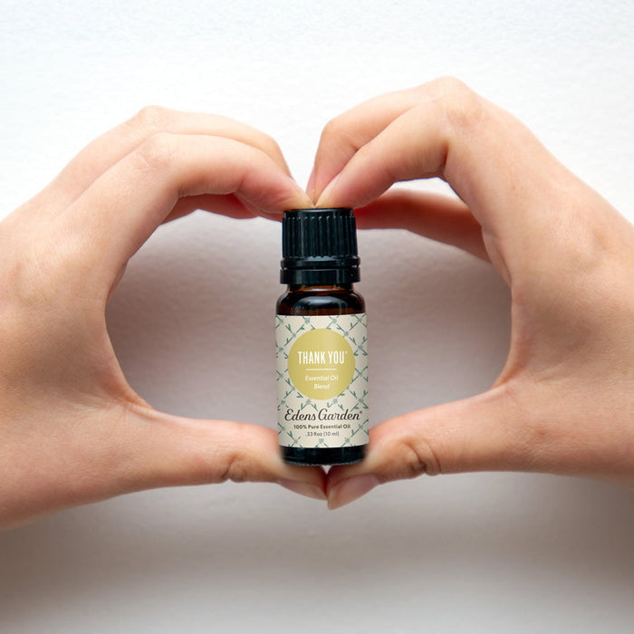 Eden's Garden essential oil bottle held between two hands against a white background